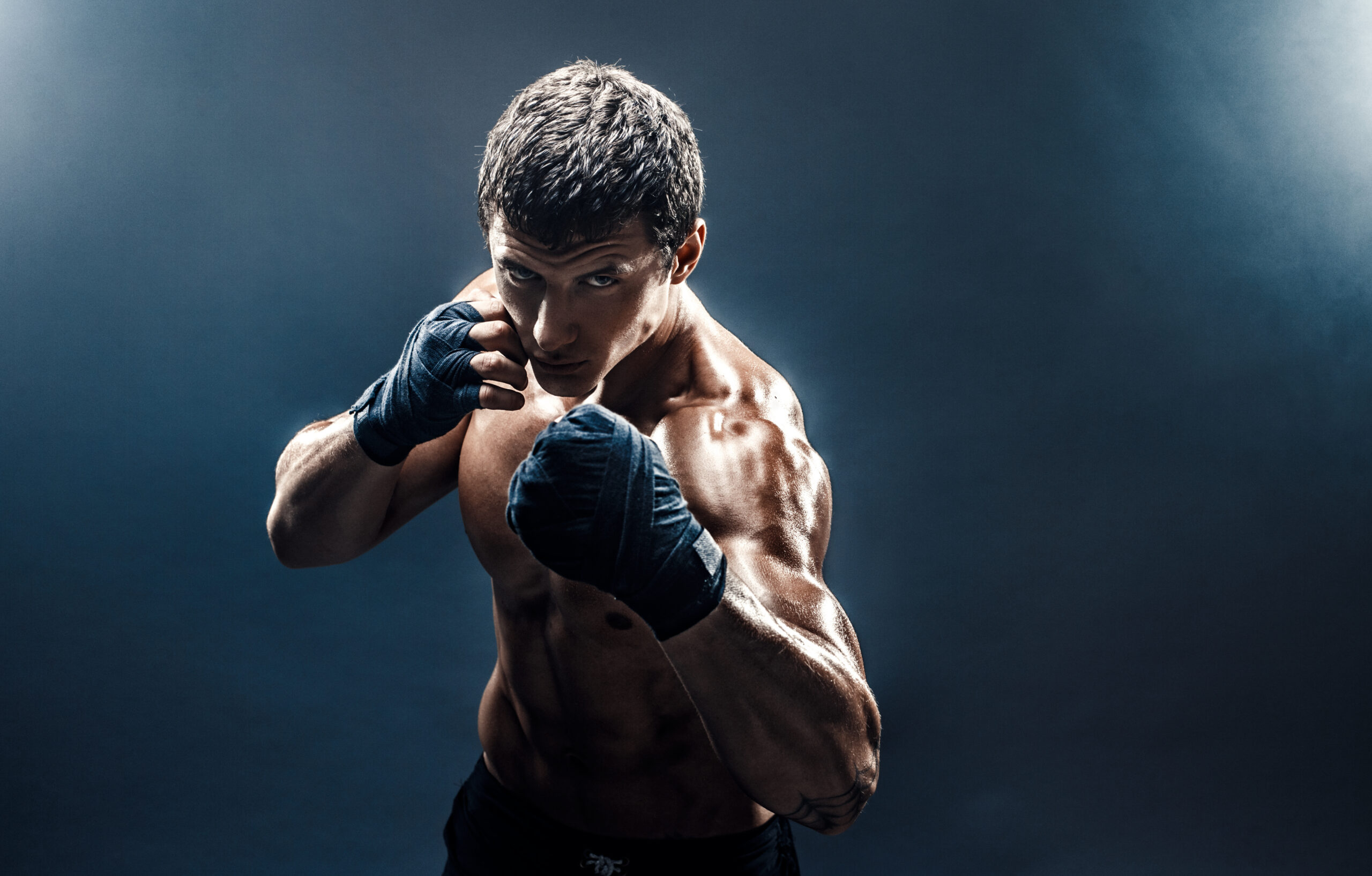 Muscular topless fighter in boxing gloves